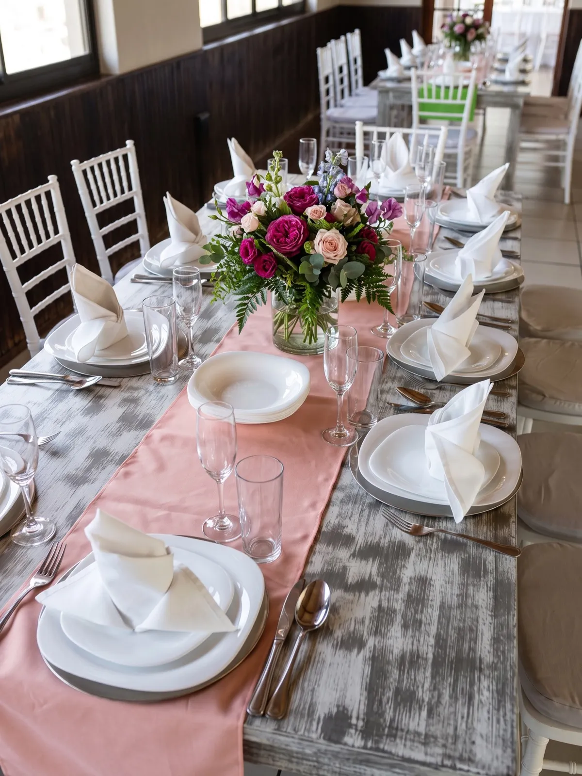 Mesa vestida en rosa con centro de flores moradas para banquete