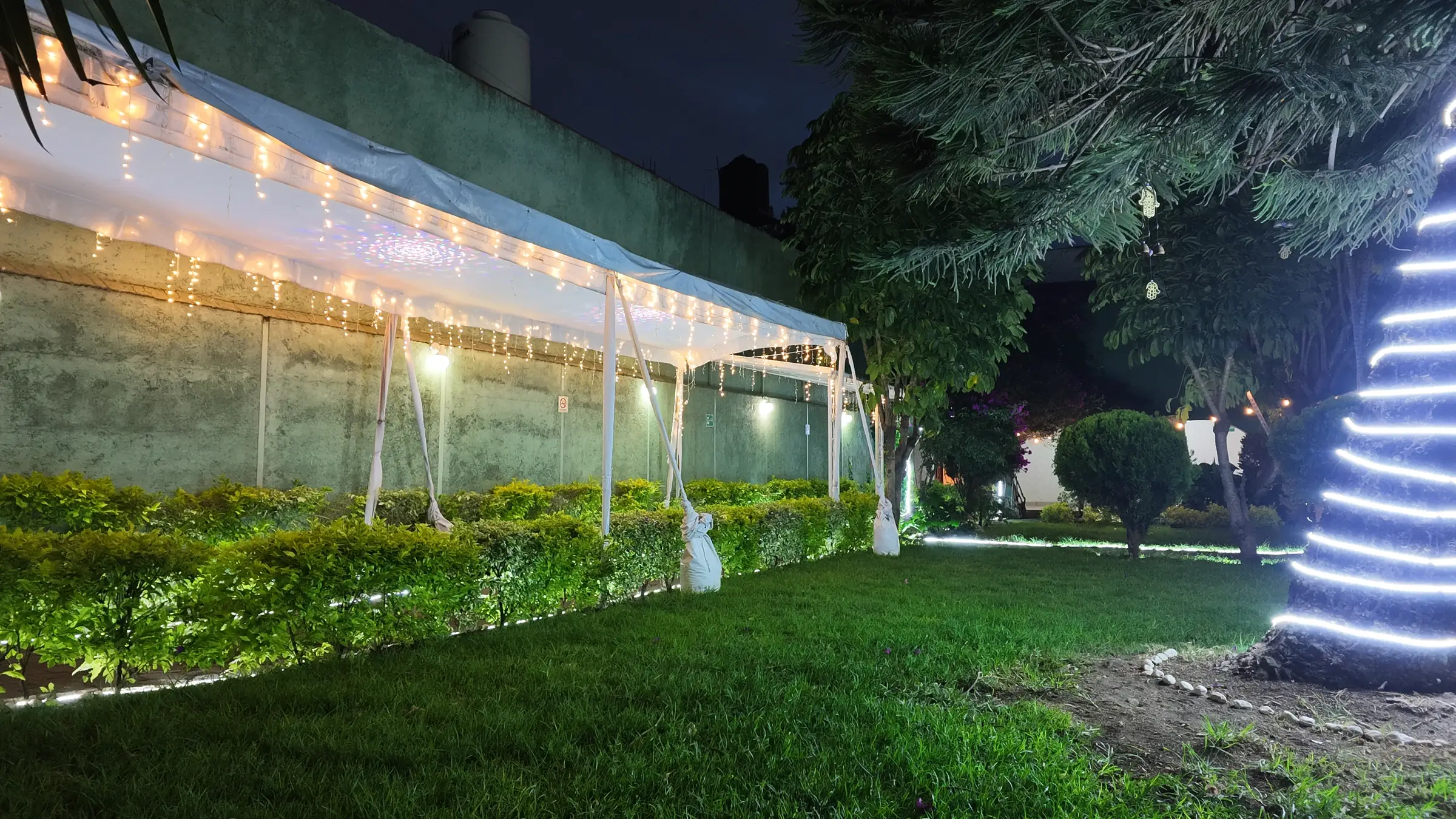 Jardín para bodas en Ciudad López Mateos — camino iluminado entre bugambilias hacia el arco de entrada, La Fuente Arboledas